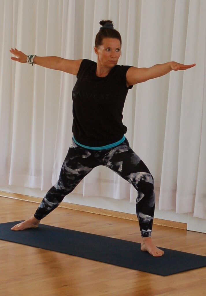 Yogalærer Mona viser krigerstilling på yogakurs.